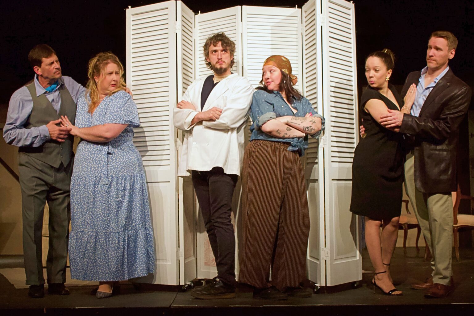 Six actors in costume around white folding screen